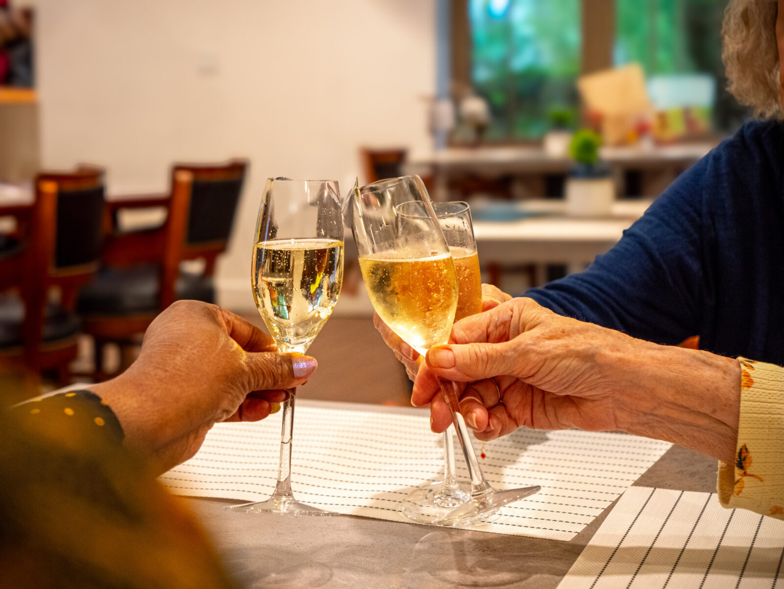 Seniors clinking champagne glasses in a cheerful toast at The Glades at ChampionsGate community
