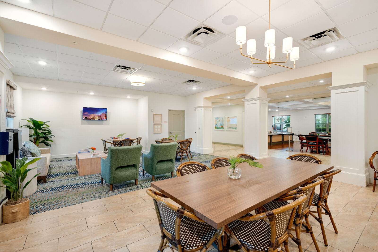 Dining area with a common area in the background featuring a flat screen television and seating