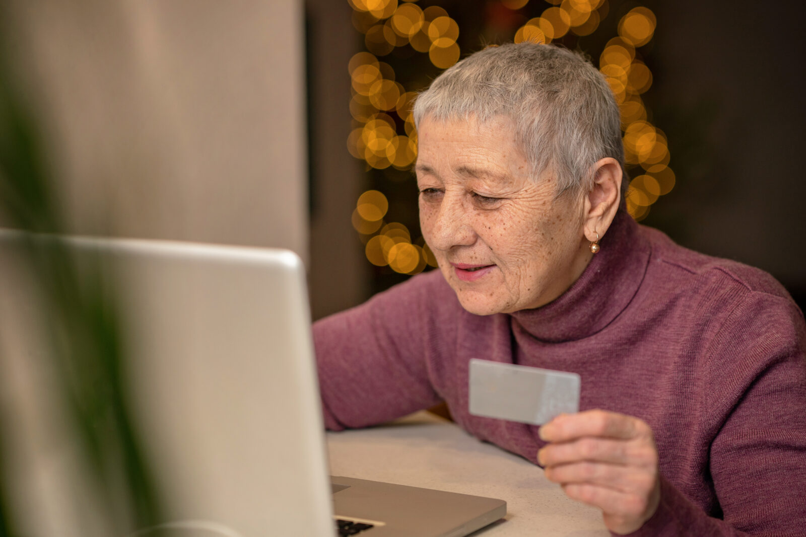 Older woman at The Glades using a laptop and holding a card while shopping online