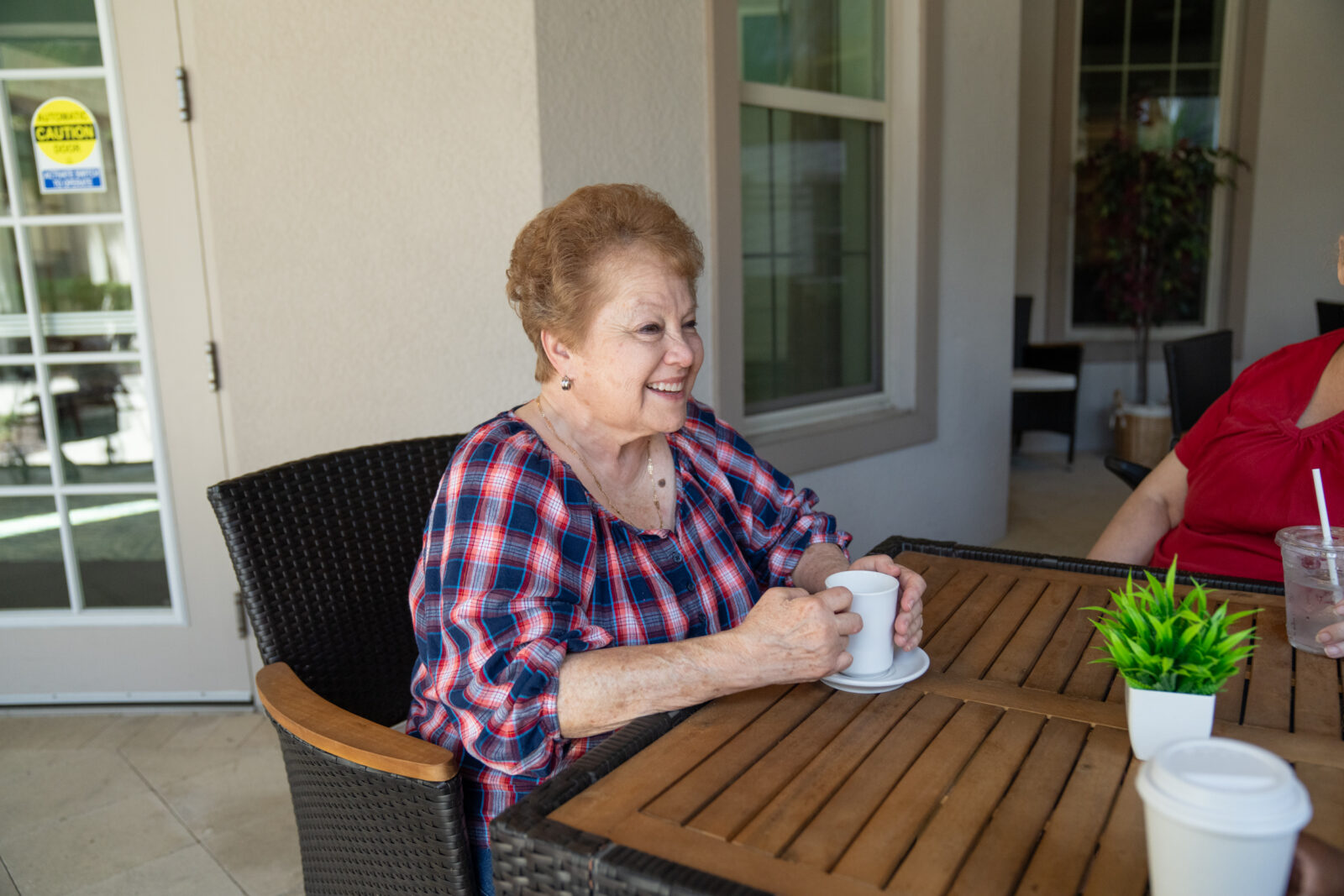 Senior resident enjoying a relaxed conversation over coffee at The Glades at ChampionsGate, a senior living community offering Independent Living, Assisted Living, and Memory Care.